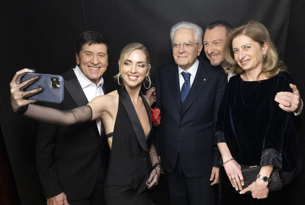 Sanremo 2023: Der Präsident der Italienischen Republik Sergio Mattarella steht zwischen Gianni Morandi, Chiara Ferragni, Amadeus und seiner Tochter Laura vor schwarzem Hintergrund. Ferragni macht ein Selfie von sich und der Gruppe.