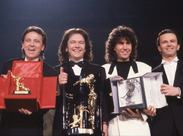 Pooh (Roby Facchinetti, Red Canzian, Stefano D’Orazio und Dodi Battaglia) präsentieren die beim Sanremo-Festival erhaltenen Preise. Die Bandmitglieder tragen Anzüge.