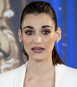 Schulterporträt von Pilar Fogliati, sie hat ihr Haar zurückgebunden, trägt eine Weiße Bluse, Ohrringe und ein Headset